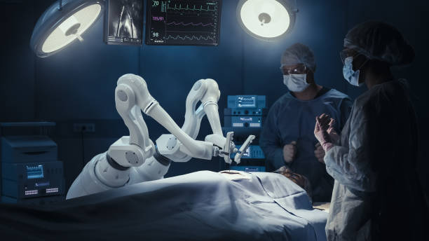 Two Surgeons Observing High-Precision Programmable Automated Robot Arms Operating Patient In High-Tech Hospital. Robotic Limbs Performing Complex Nanosurgery, Doctors Looking At Vitals On Monitor.