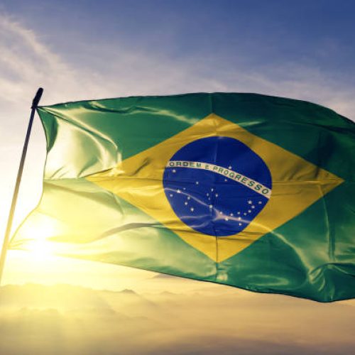 Brazil Brazilian flag on flagpole textile cloth fabric waving on the top sunrise mist fog